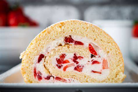 Fertig gebackene Erdbeerroulade mit Puderzucker und frischen Erdbeeren dekoriert