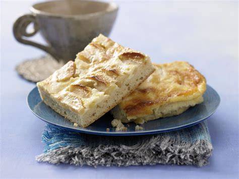 Fertig gebackener Apfelkuchen mit Sauerrahmguss auf einer Kaffeetafel