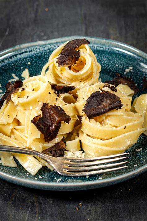 Fertige Trüffelsauce auf Pasta angerichtet, mit Trüffelspänen und Parmesan