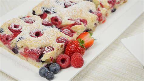 Fertiger Blechkuchen mit Puderzucker und frischen Beeren
