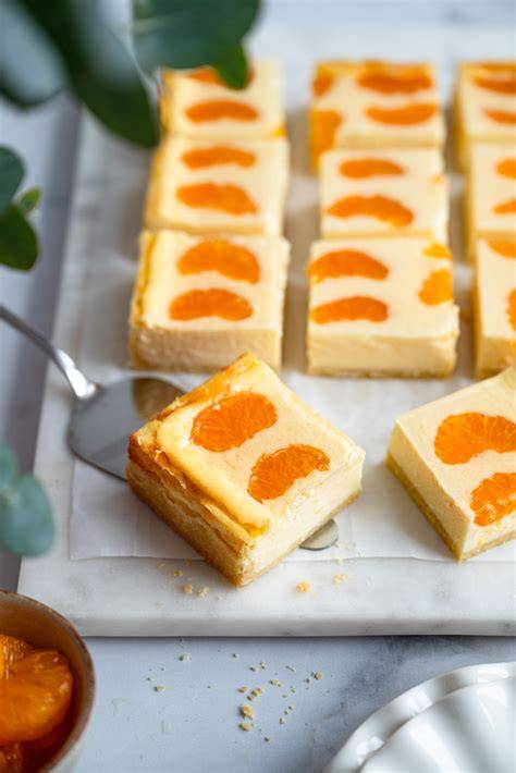 Fertiger Käsekuchen vom Blech mit Mandarinenstücken auf rustikalem Holzbrett