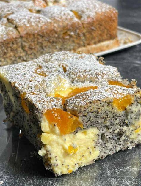Fertiger Pfirsich Mohn Quark Kuchen auf einem Kuchenteller mit Puderzucker bestäubt