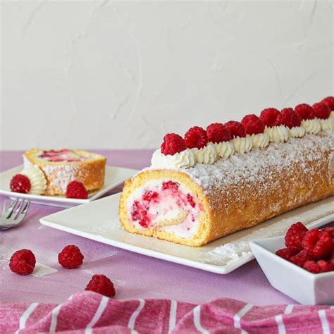 Festlich dekorierte Himbeer-Biskuitrolle mit Mascarponefüllung und frischen Himbeeren