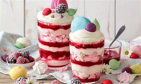 Festliches Rahm-Meringue-Dessert mit bunten Macarons und Himbeeren