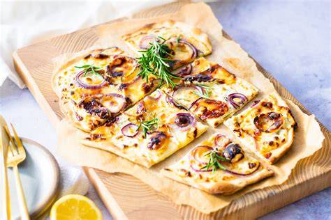 Flammkuchen mit Ziegenkäse, Rosmarin und Honig auf Holzbrett