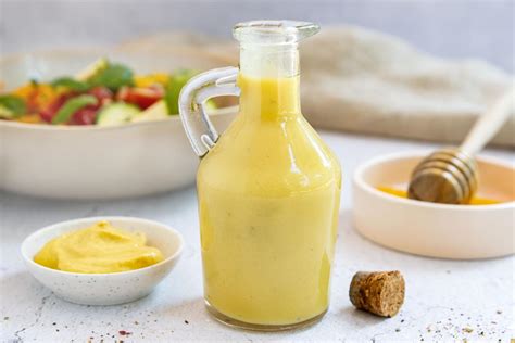 Flasche Honig-Senf-Dressing und Zutaten (Senf, Honig, Apfelessig, Zitrone)