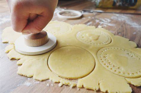 Fondant-Aufleger werden auf Kekse geklebt