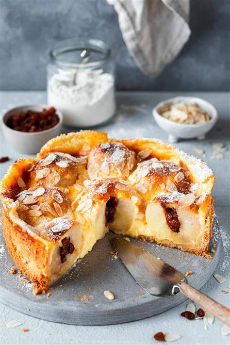 Foto: Bratapfelkuchen angeschnitten mit sichtbaren ganzen Äpfeln und Vanillepudding