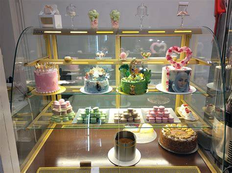 Foto: Vitrine mit mehrstöckigen Torten, Spiegelglasuren und Fondantblüten