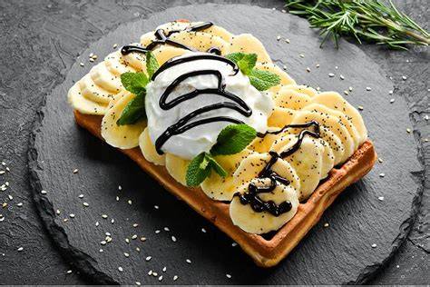 Foto einer goldbraunen Bananenwaffel mit Mandelsplittern und Sahne