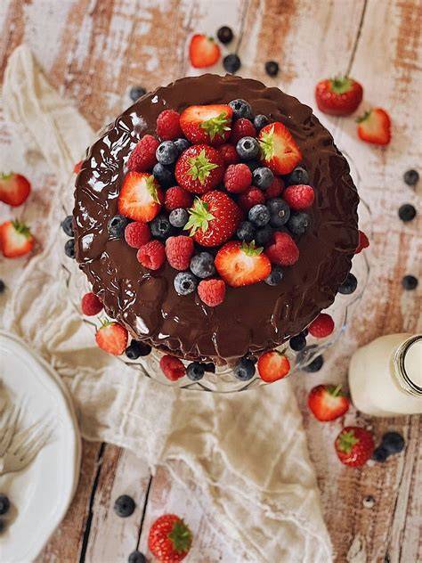 Foto eines Schoko Cheesecakes mit glänzender Schokoladenganache und frischen Beeren als Topping