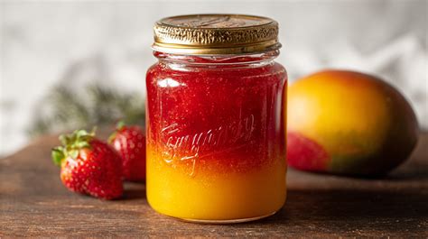Frühstücksbrett mit Brotscheiben und Mango-Erdbeer-Marmelade im Glas