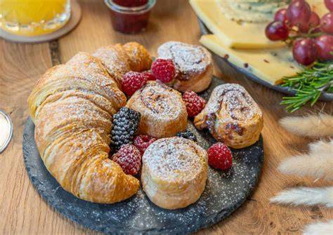 Frühstücksteller mit Croissant, Pralinen und Früchten
