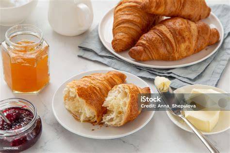 Frühstückstisch mit Aufback-Croissants, Butter und Marmelade