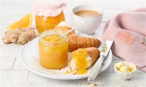 Frühstückstisch mit Marmeladenglas, Baguette, Quark und Orangen