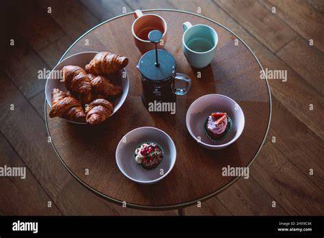 Frühstückstisch mit Nuss-Nougat-Creme, Brot, Croissants und Tassen Kaffee