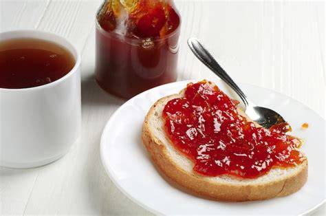 Frühstückstisch mit Physalis Marmelade, frischem Brot und Tee