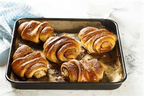 Franzbrötchen auf Backblech, Zimt und Zucker nebenbei