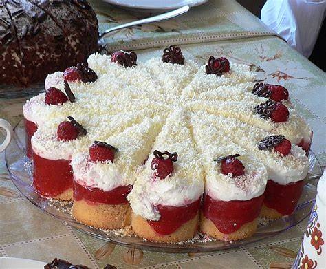 Frau Holle Kuchen in der Springform dekoriert mit weißen Schokoraspeln und frischen Erdbeeren