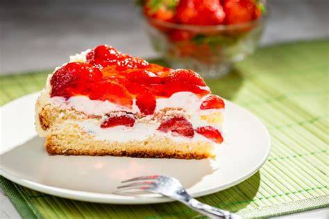 Frisch angeschnittene Erdbeertorte mit rotem Tortenguss und Sahnecreme