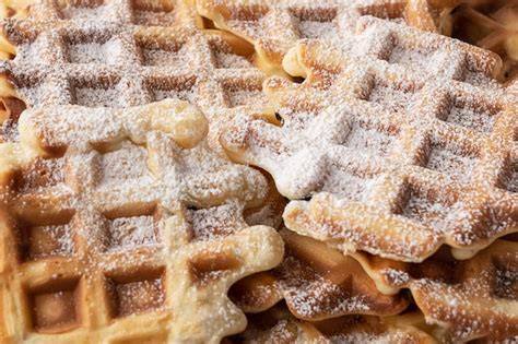 Frisch gebackene Buttermilchwaffeln mit Puderzucker auf rustikalem Brett