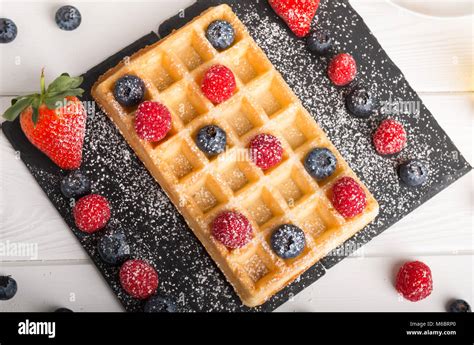 Frisch gebackene Muffin-Waffeln auf einem Gitter, daneben Toppings und bunte Streusel
