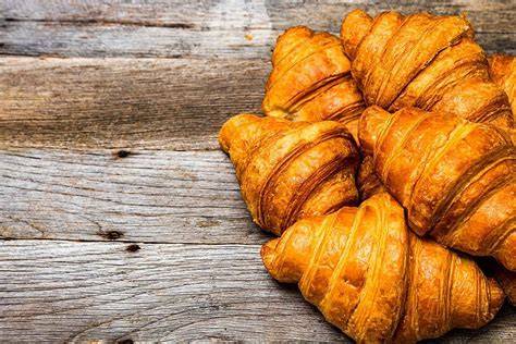 Frisch gebackene Nuss-Croissants auf einem Holzbrett mit Haselnüssen und Zimtstangen