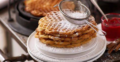 Frisch gebackene Waffeln mit warmem Apfelkompott, Zimtstange und Puderzucker