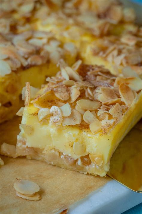 Frisch gebackener, goldgelber Apfel-Schmand-Kuchen mit Mandeln und Zimtzucker leicht bestäubt