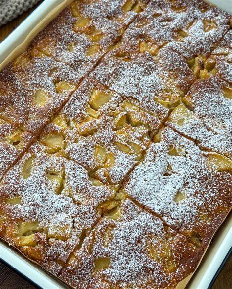 Frisch gebackener Apfelkuchen vom Blech mit Puderzucker bestäubt