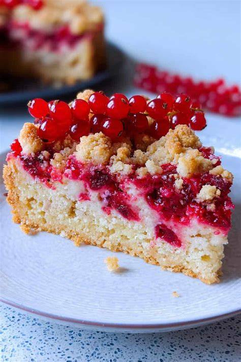 Frisch gebackener Johannisbeerkuchen mit goldbraunen Streuseln auf Teller