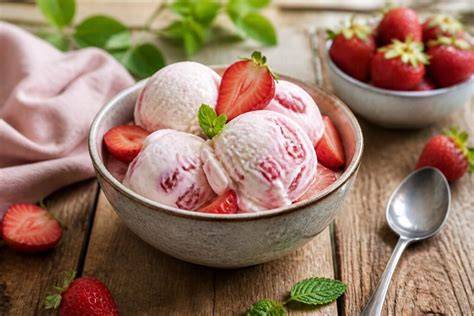 Frisch zubereitetes Bananensorbet in einer Schüssel mit Erdbeeren und Minzblättern