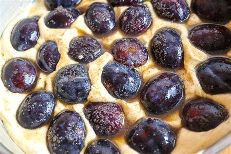 Frische, glänzende Pflaumenviertel auf Kuchenteig