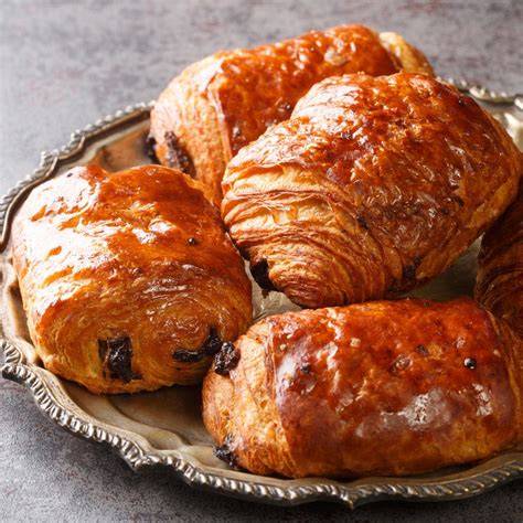Frische, selbstgemachte Schokocroissants auf einem Backblech mit glänzendem Eigelb-Anstrich