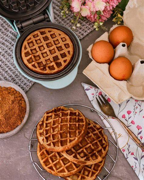 Frische Bananen, Quark und Eier als Zutaten für Waffeln, daneben ein vorgeheiztes Waffeleisen