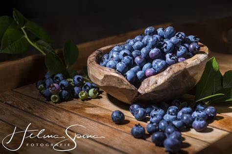 Frische Blaubeeren und Buchweizenmehl in traditioneller Holzschale