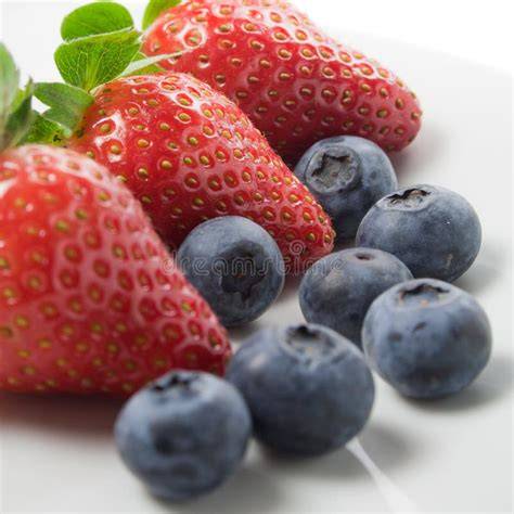 Frische Erdbeeren und Blaubeeren in einer Schale, daneben Limetten und Gelierzucker