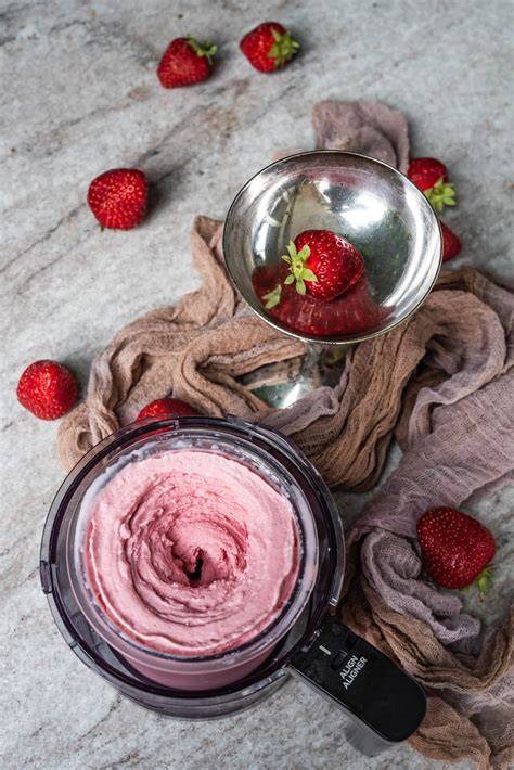 Frische Erdbeeren und Ninja Creami Mixbehälter mit Erdbeereis-Masse