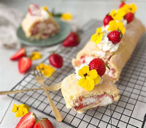 Frische Erdbeeren und eine angerichtete Biskuitrolle auf einer Sommerkuchentafel