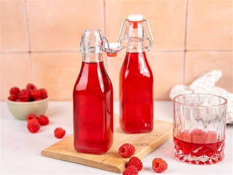 Frische Himbeeren und Himbeerkonzentrat in Flaschen