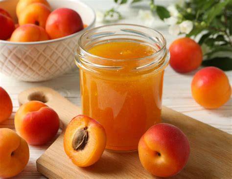 Frische Marillen und Marmeladegläser auf einem Holztisch