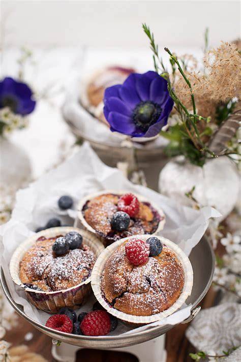 Frische Muffins im Picknickkorb mit Beeren und Ahornsirup