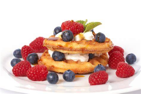 Frische gebackene Softwaffeln auf Holztisch, mit Beeren und Sahne serviert