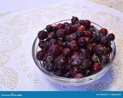 Frische und gefrorene Johannisbeeren in einer Schale, Backutensilien im Hintergrund
