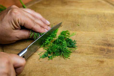 Frischer Dill und Zitronenhälfte auf Holzbrett