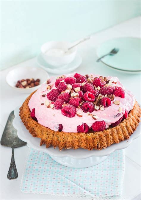 Frischer Himbeer Mascarpone Kuchen auf einem Tisch, umgeben von Backzutaten