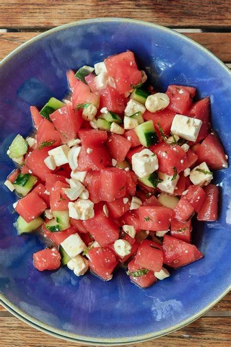 Frischer Melonen-Feta-Salat, angerichtet auf einem rustikalen Holztisch mit Zutaten