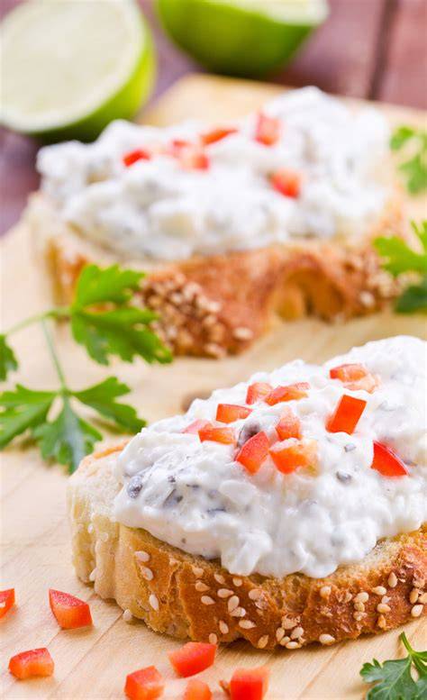 Frischkäse-Dip, Honig, Kräuter und Brotscheiben auf einem rustikalen Frühstückstisch