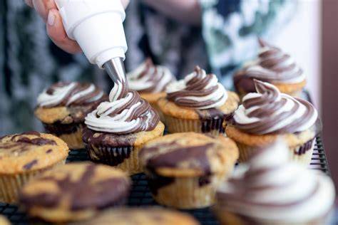 Frosting wird mit Spritzbeutel auf Schoko Cupcakes aufgetragen
