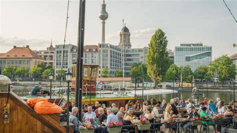 Gäste auf der Terrasse an der Spree mit Blick auf Ausflugsschiffe und das Reichstagsufer